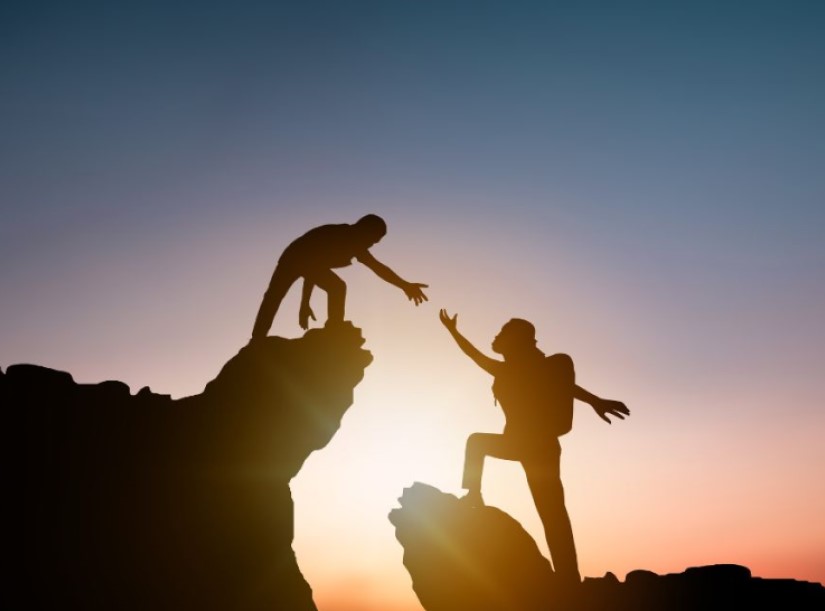 Person reaching out to help someone climb